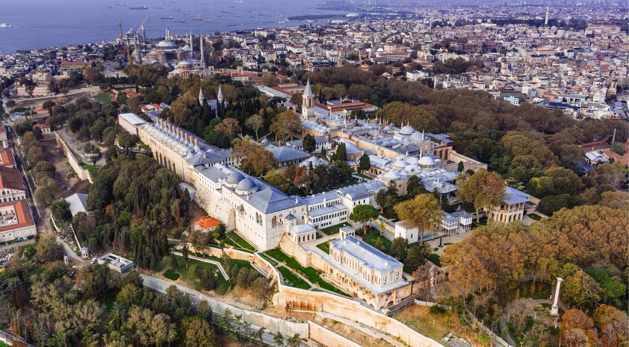 Aerial view of the whole Topkapi Palace complex on its wooded headland above Istanbul, with the Golden Horn and the city beyond