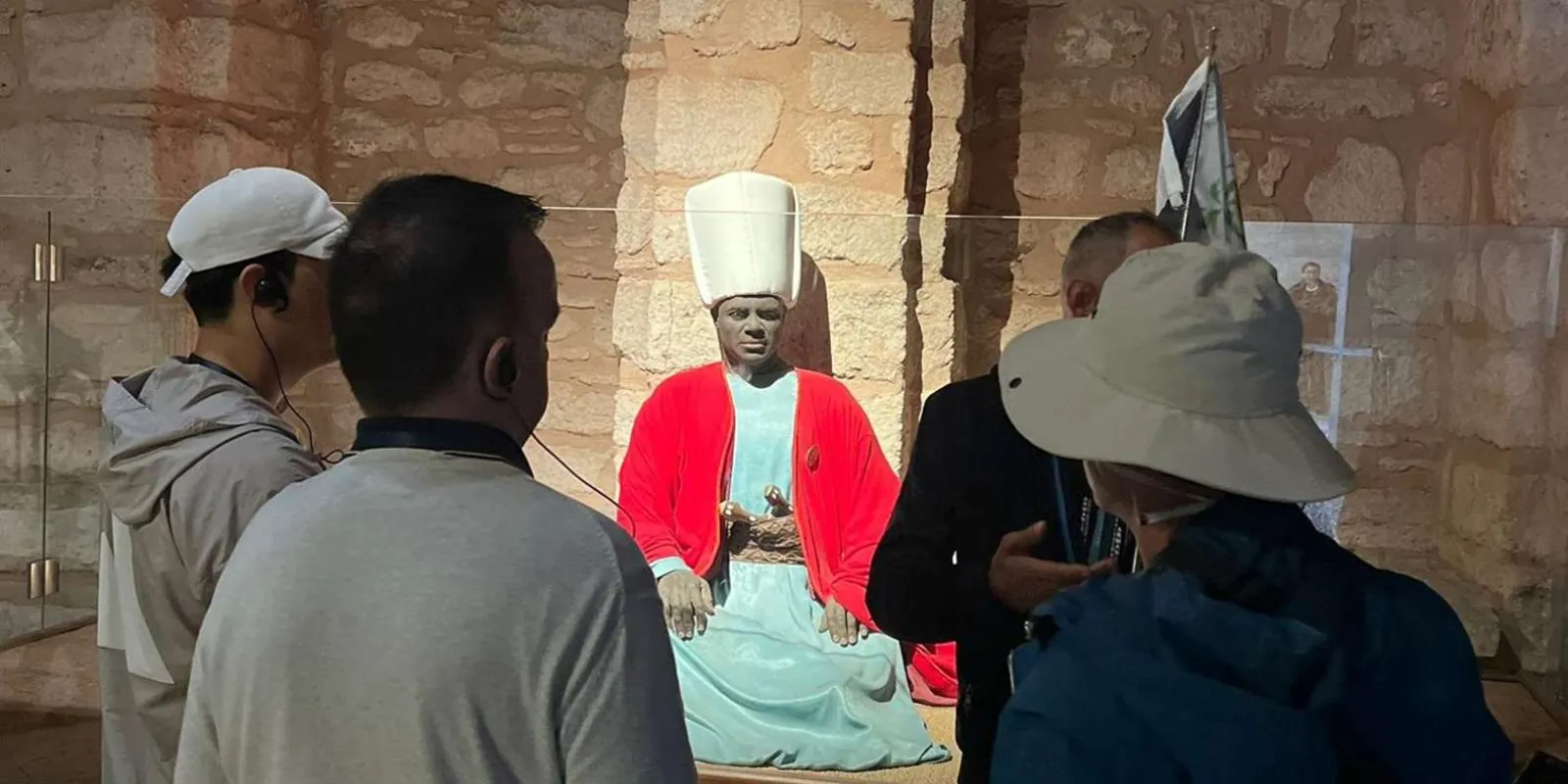 A tour group viewing a costumed figure of a palace official in a stone-vaulted display room at Topkapi Palace