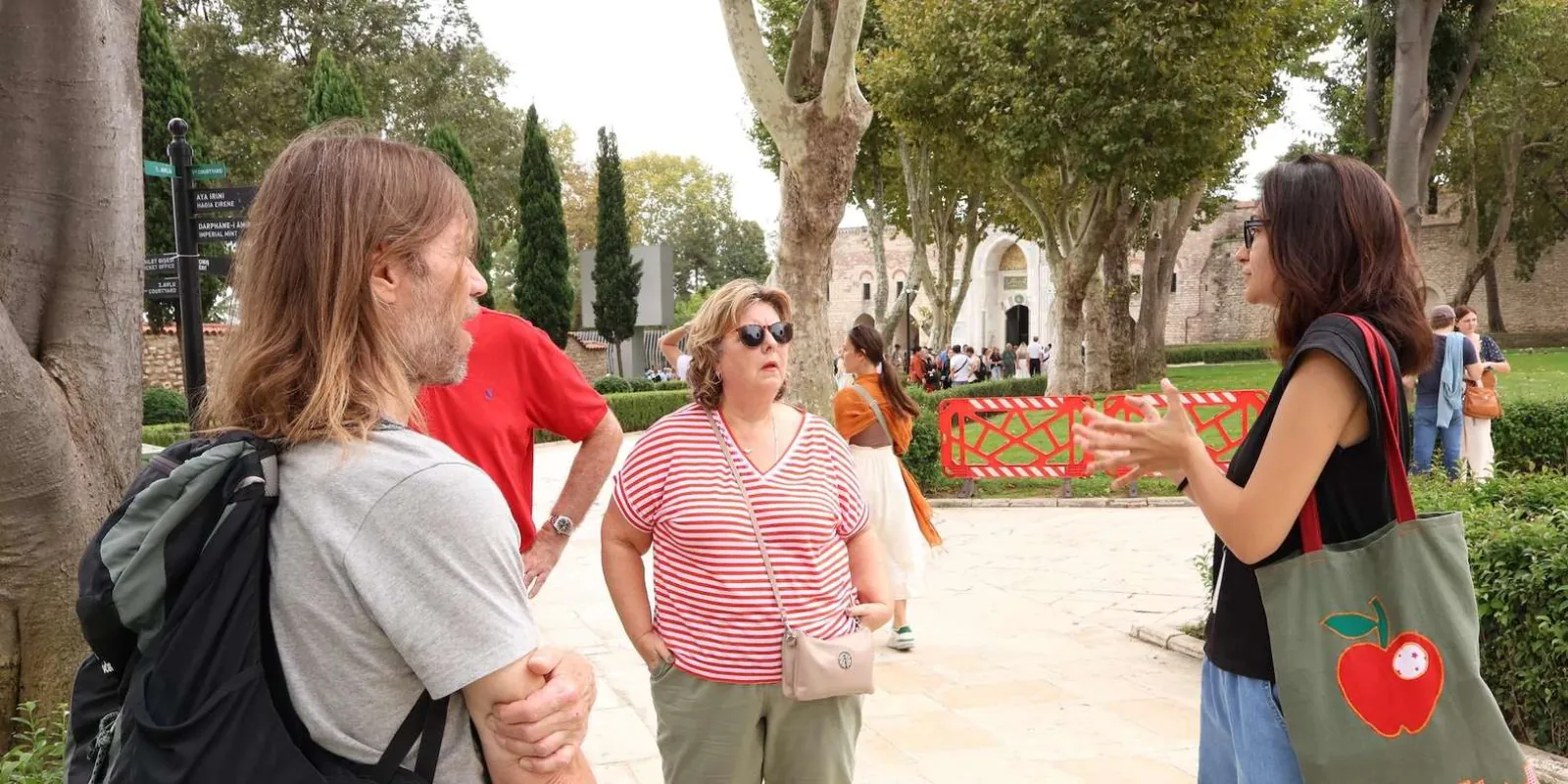 A guide briefing two travellers in the First Court of Topkapi Palace, with the Gate of Salutation behind them
