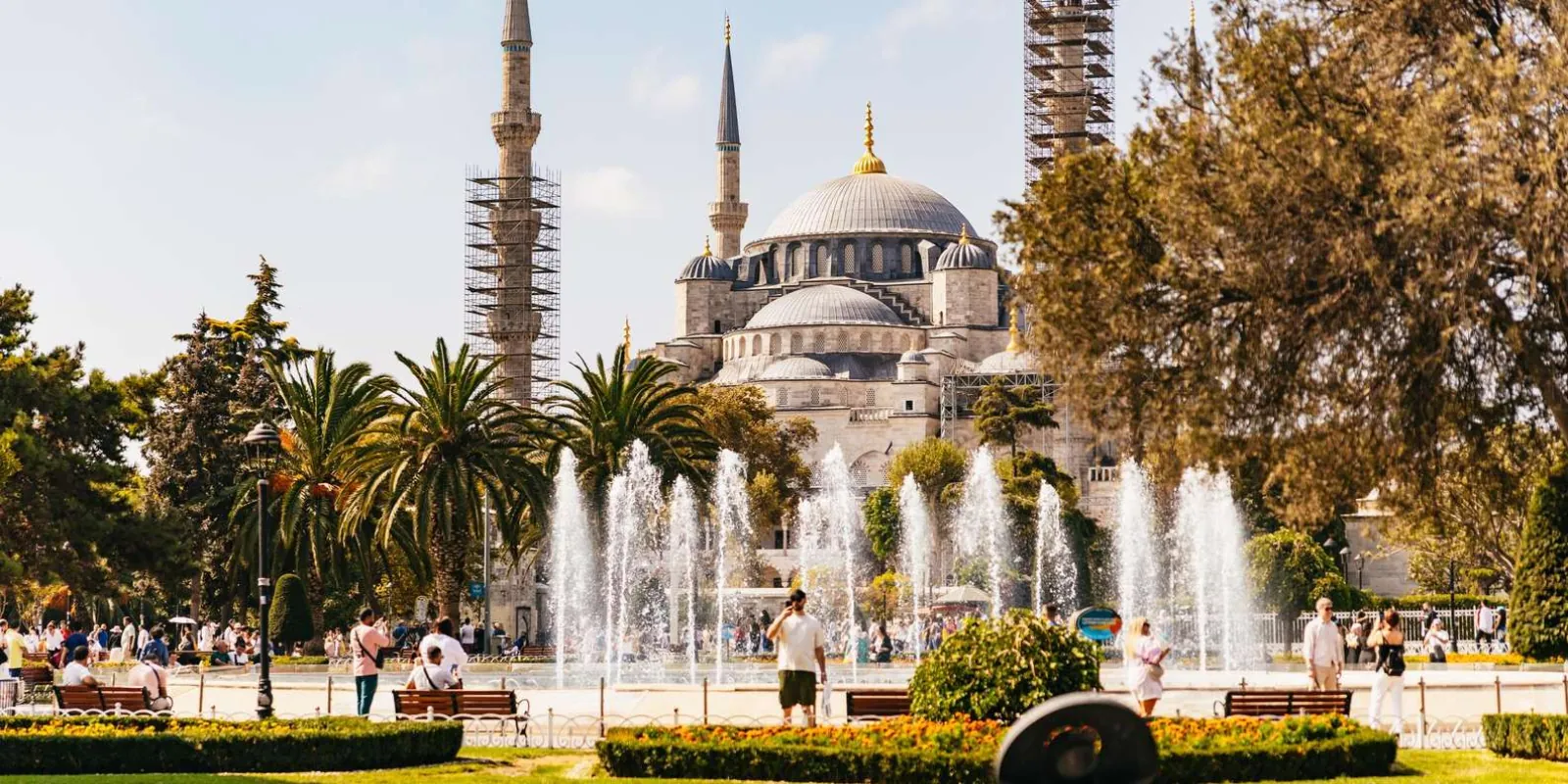 The Blue Mosque behind the fountains of Sultanahmet Park, with scaffolding on two minarets