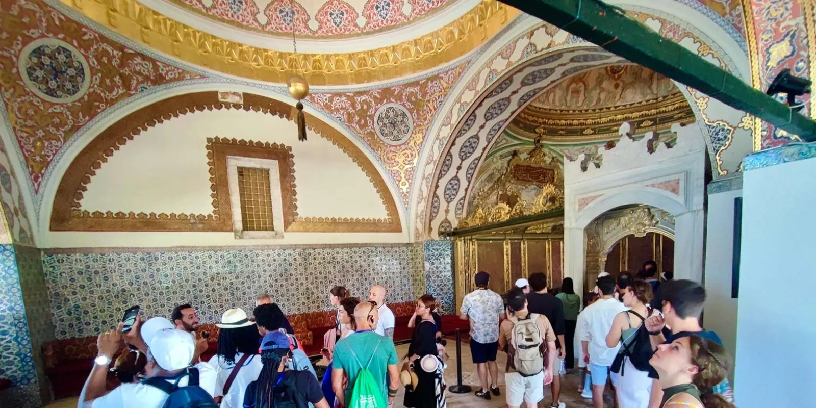 Visitors beneath the painted and gilded dome of the Imperial Council chamber at Topkapi Palace