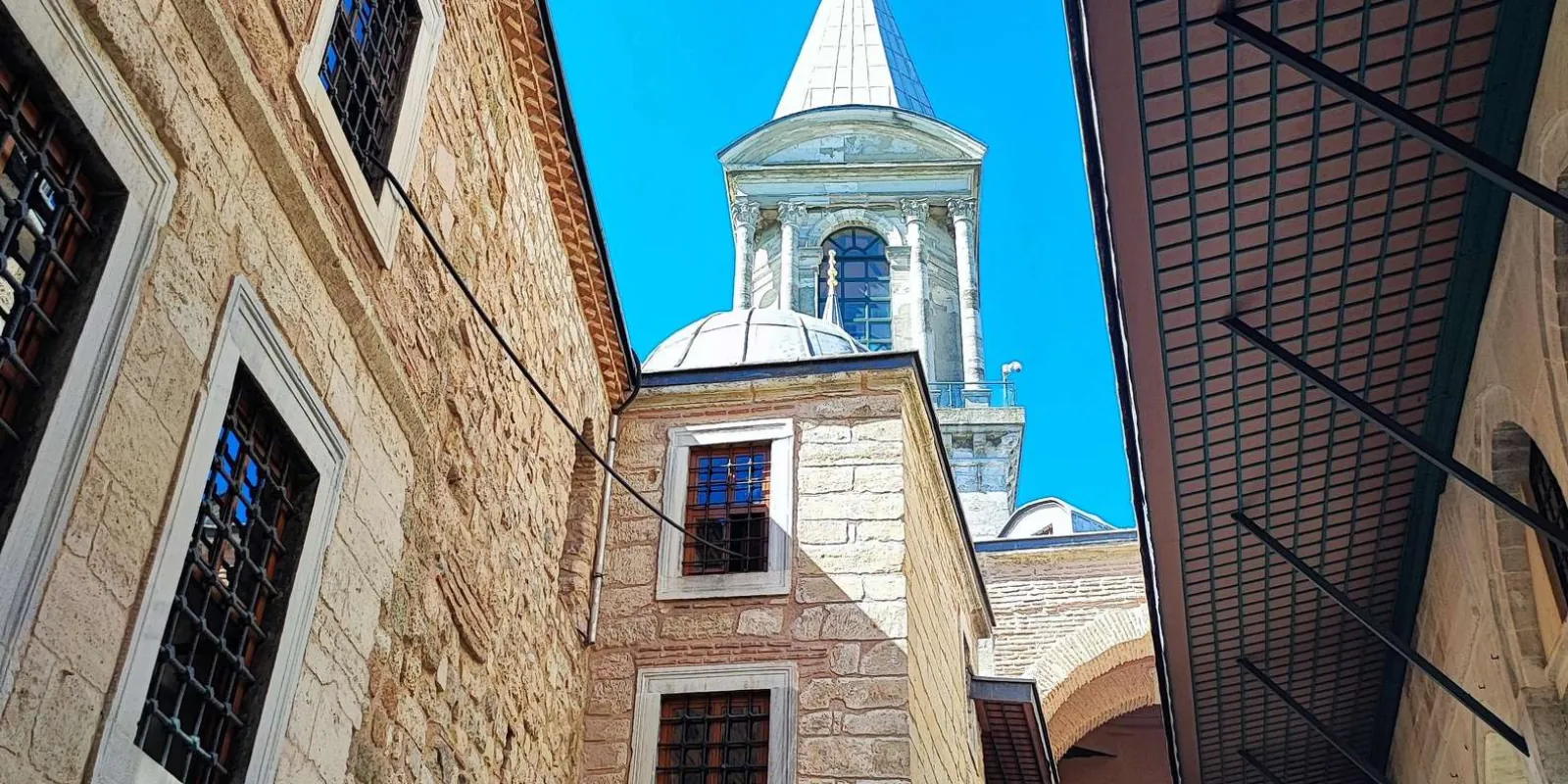 Looking up between stone walls to a domed pavilion tower inside the Topkapi Palace complex
