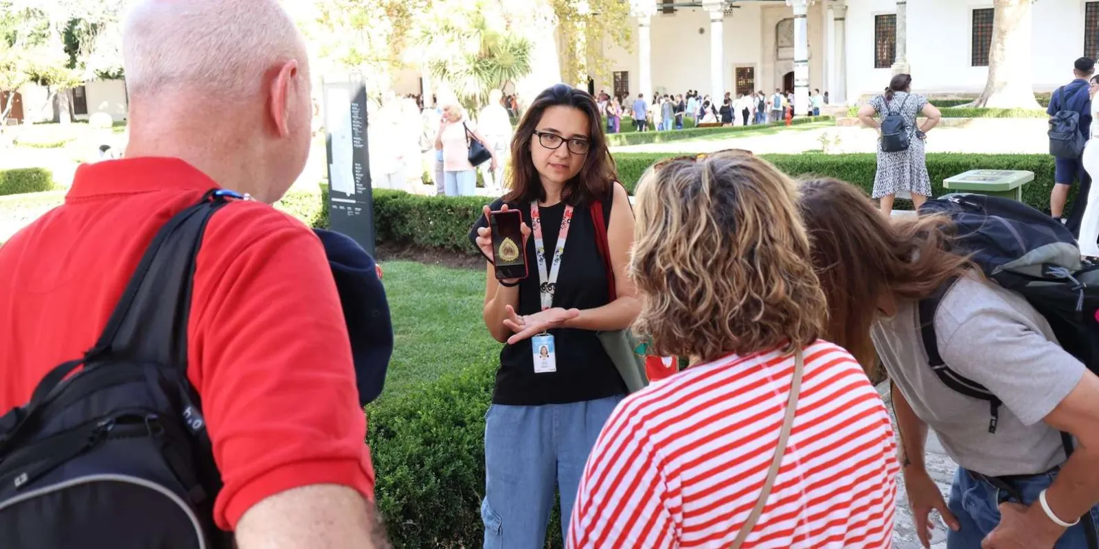 A licensed guide showing an image on her phone to a small group in a Topkapi Palace courtyard