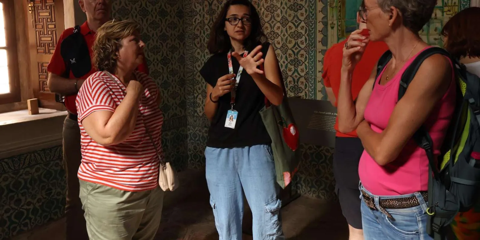 A guide explaining an Iznik tile panel to travellers inside a Topkapi Palace room