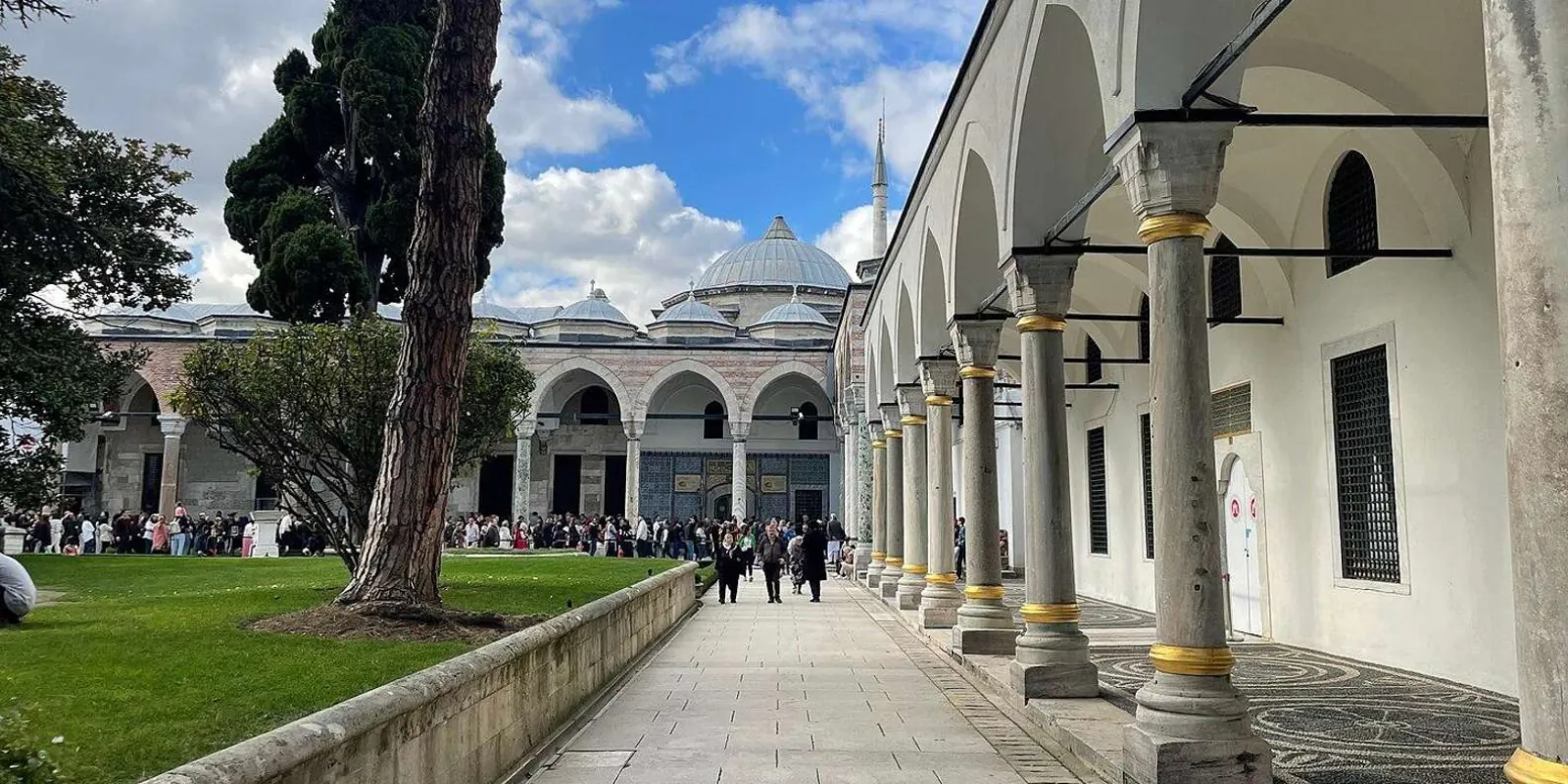 The colonnade of the Third Court at Topkapi Palace, with visitors queuing outside a domed pavilion