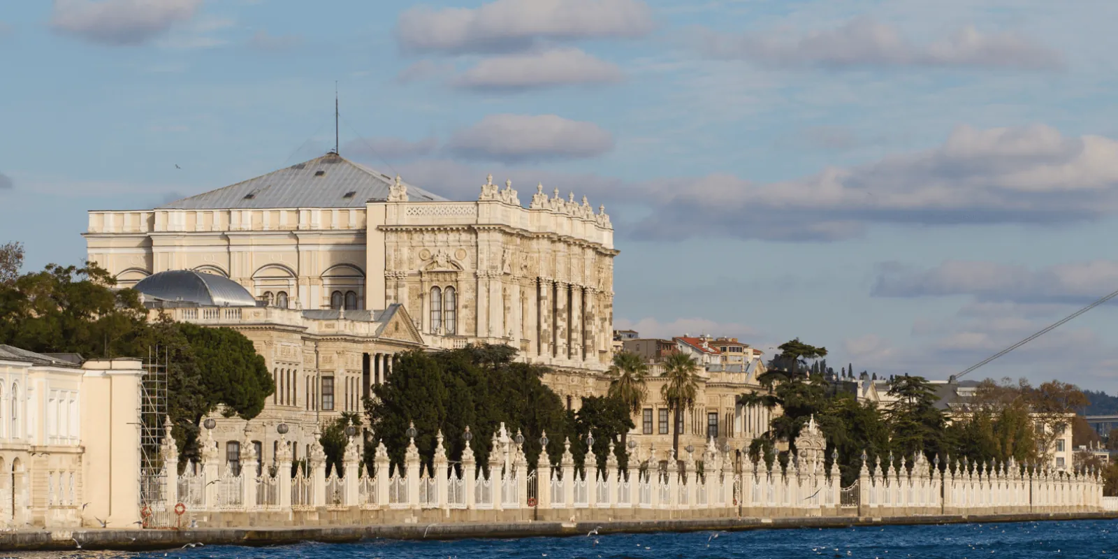 Dolmabahce Palace and its white waterfront railing seen from the Bosphorus in late afternoon light